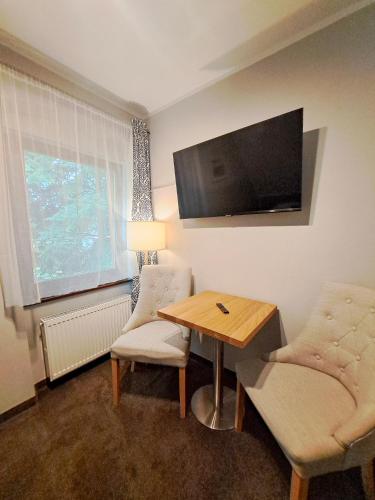 a living room with a table and a television on the wall at Pensjonat Pod Świerkami in Polanica-Zdrój