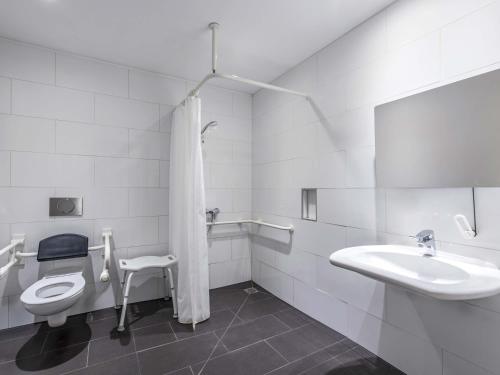 a white bathroom with a toilet and a sink at B&B Hotel München-Olympiapark in Munich