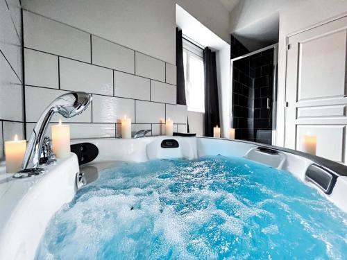 a bathroom with a tub with blue water in it at Suite Balnéo Privée Design Calme Proche Lille in Roubaix