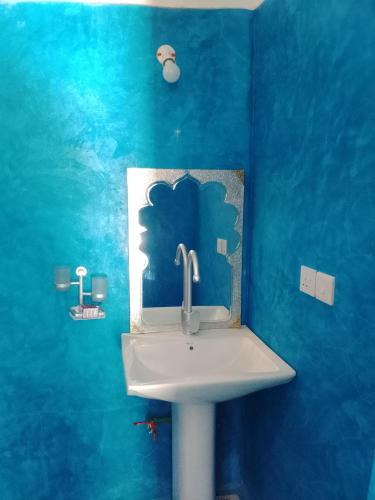 a bathroom with a sink in a blue wall at NEW ORANGE APARTMEnt in Jambiani