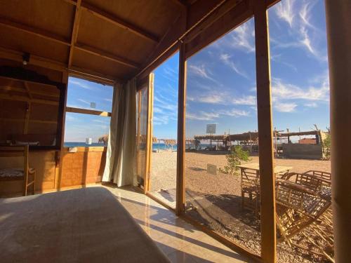 a room with a view of the beach through glass at Mishmish wood house in Nuweiba