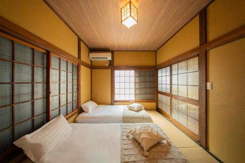 two beds in a room with two windows at 日本の生活を体験できる古民家 一棟貸切最大7名 jr上中里駅 in Tokyo