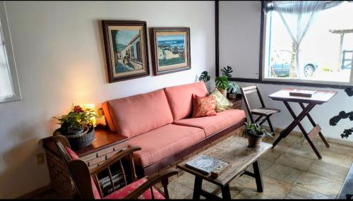 a living room with a pink couch and a table at Casinhas do Peró Refúgio com Jardim e WiFi Rápido in Cabo Frio