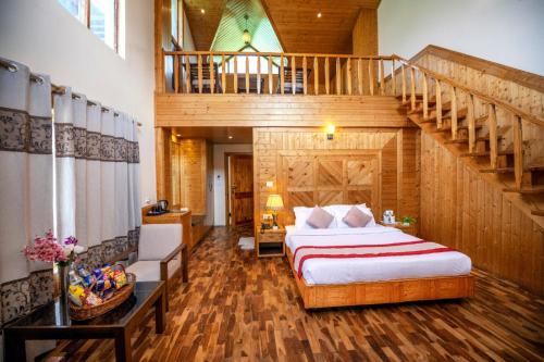 a bedroom with a large bed and a staircase at Azure Chandertal Regency Hotel And Spa in Manāli