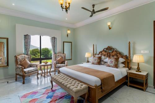 a bedroom with a bed and a chair and a window at Dilip Niwas in Udaipur
