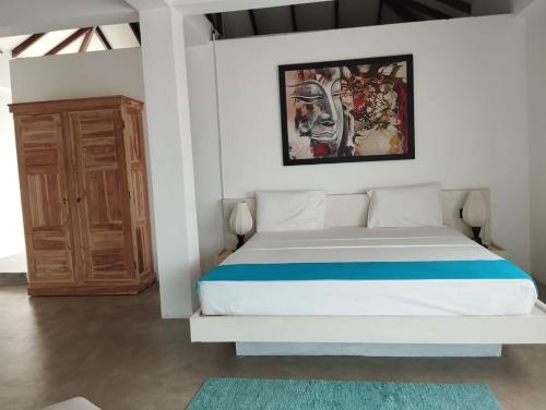 a bedroom with a bed and a painting on the wall at The Beach house by Kay Jay Hotels in Pasikuda