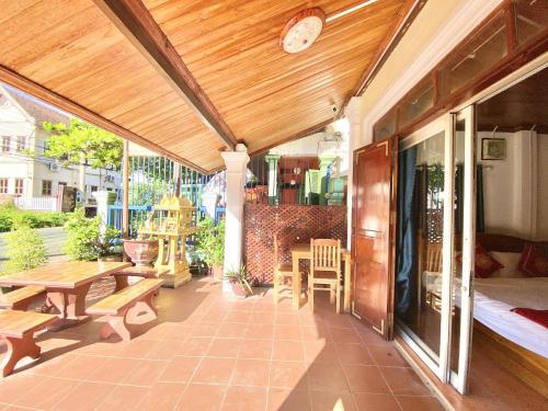 a patio with a table and benches and a clock at Villa That Luang Legend in Luang Prabang