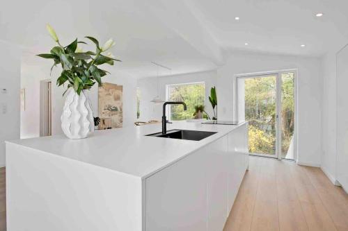 a white kitchen with a sink and a vase with a plant at Exclusive First Floor with Designer Touches in Kongens Lyngby