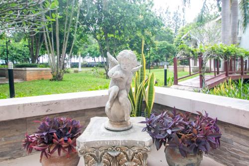 a statue of an angel sitting next to some flowers at Baan Rub Lom by Jane in Pak Chong