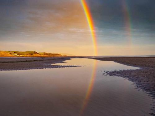 a rainbow in the sky over a body of water at Fairladies Barn Guest House in St Bees