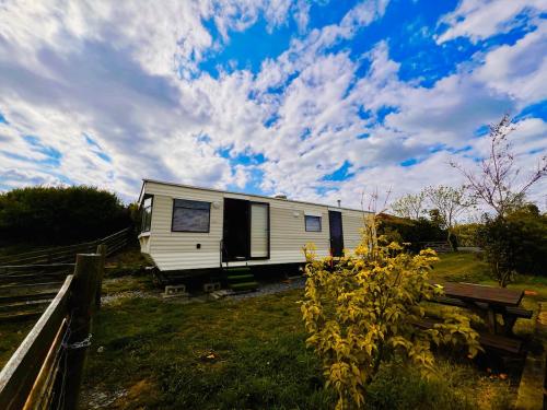 a white trailer parked in a field under a cloudy sky at A static haven in Caernarfon