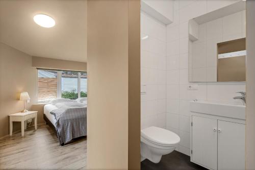 a bathroom with a bed and a toilet and a sink at Reykjadalur Guesthouse in Hveragerði
