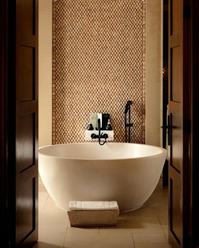 a white bath tub in a bathroom with a tile wall at Banyan Tree Tamouda Bay in Fnidek