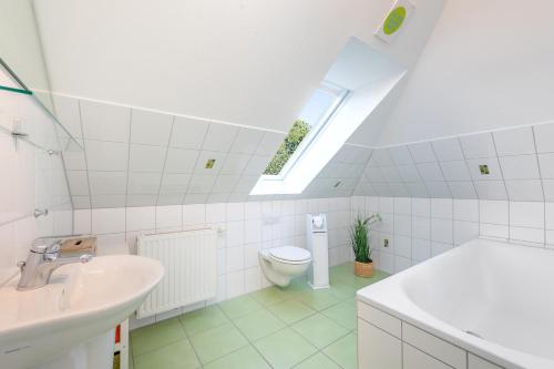 a bathroom with a toilet and a sink and a window at 6 East Ferienhaus in Niendorf