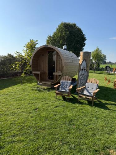 two chairs in front of a circular house in a field at Privé Glamping & wellness Moonlight in Brakel