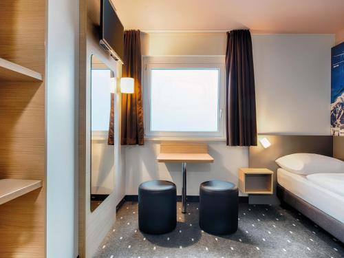 a small room with a bed and a desk at B&B HOTEL München-Airport in Hallbergmoos