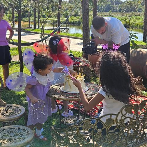 a man and two little girls standing around a table with a cake at Iveria Parky and cottages in Shekvetili