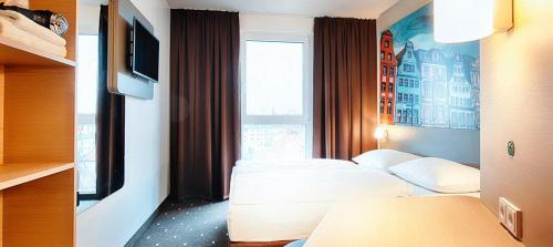 a hotel room with two beds and a window at B&B Hotel Rostock City-West in Rostock