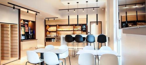 a dining room with white tables and white chairs at B&B Hotel Rostock City-West in Rostock