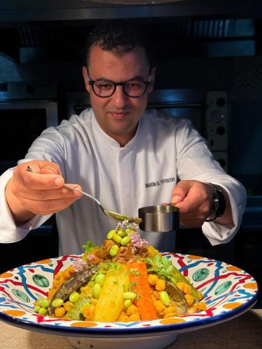 a man eating a plate of food with a fork at Banyan Tree Tamouda Bay in Fnidek