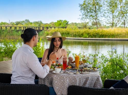 a man and woman sitting at a table with food at Banyan Tree Tamouda Bay in Fnidek