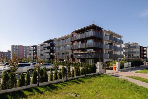 an apartment building with cars parked in a parking lot at Nowoczesny Apartament w Gliwicach z Umeblowanym Balkonem by Noclegi Renters in Gliwice