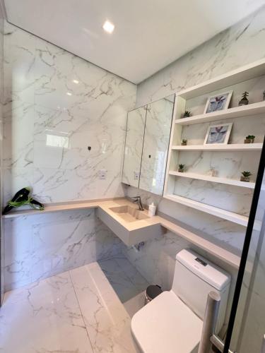 a white bathroom with a toilet and a sink at Suíte standard privado in Balneário Camboriú