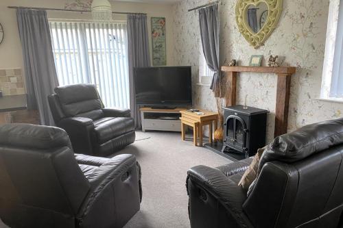 a living room with two leather chairs and a television at Cozy Dog Friendly cottage near Bridlington in Bridlington