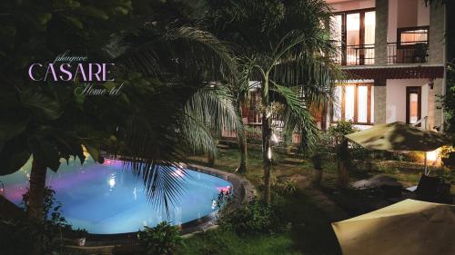 a swimming pool in front of a house with palm trees at Casare Phu Quoc - Formerly Caesar Hotel in Phu Quoc