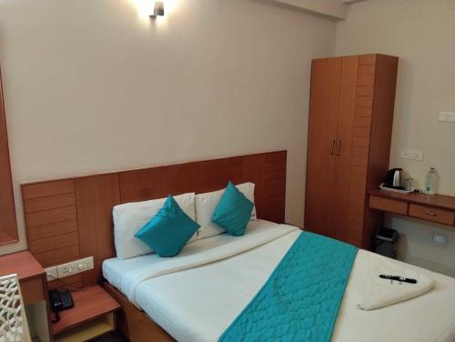 a bedroom with a large bed with blue pillows at Hotel O RKH Residency in Chennai