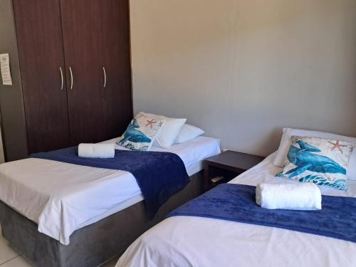 a room with two beds with blue and white sheets at SeaXplore Lodge & Dive Center in Sodwana Bay