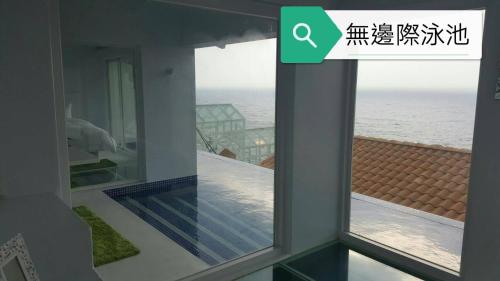 a window in a house with a view of the ocean at Ample Villa 小希臘民宿 in Ruifang