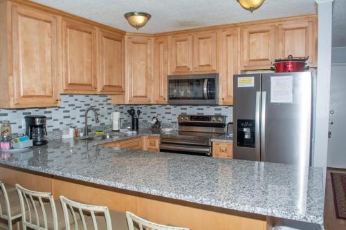 a kitchen with wooden cabinets and a stainless steel refrigerator at Winterplace Condos - Ski in Ski out E104 in Ghent
