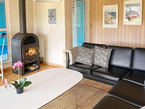 a living room with a black leather couch and a wood stove at 4 star holiday home in Nordborg in Nordborg