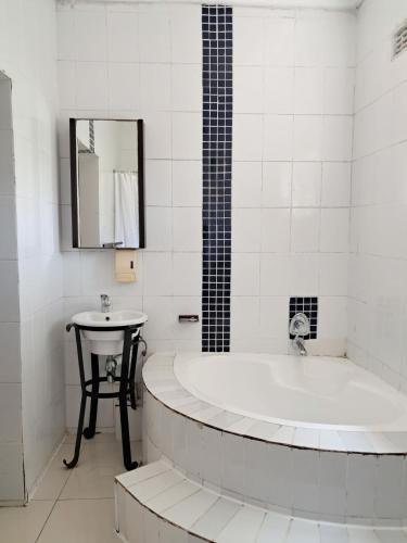 a white bathroom with a tub and a sink at SeaXplore Lodge & Dive Center in Sodwana Bay