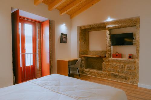 a bedroom with a bed and a desk and a television at Hotel Recanto do Avia in Ribadavia