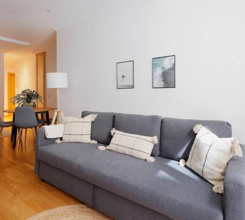 a living room with a gray couch with pillows at Suite Centro By Silastur in Gijón