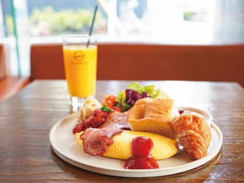 een bord met ontbijtproducten en een glas sinaasappelsap bij Agora Place Tokyo Asakusa in Tokyo