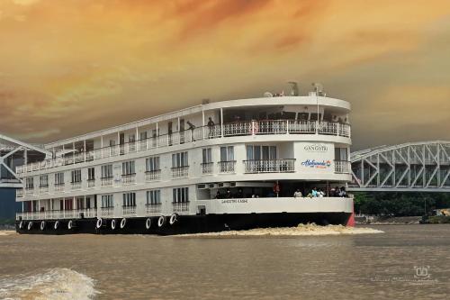 a cruise ship on the water near a bridge at Gangotri - A Divine River Retreat in Varanasi