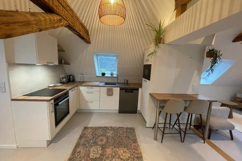 a kitchen with white cabinets and a table and chairs at La Girouette in the heart of a farmhouse in Mittelhausbergen