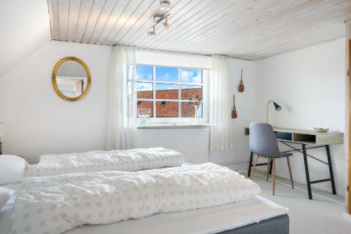a bedroom with two beds and a desk and a window at Vrenstedvej 21A in Løkken