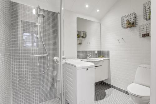 a white bathroom with a shower and a toilet at Den Skæve Linje 4C in Løkken