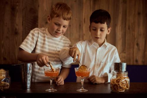 two boys are making a drink at a table at COMO Alpina Dolomites in Alpe di Siusi