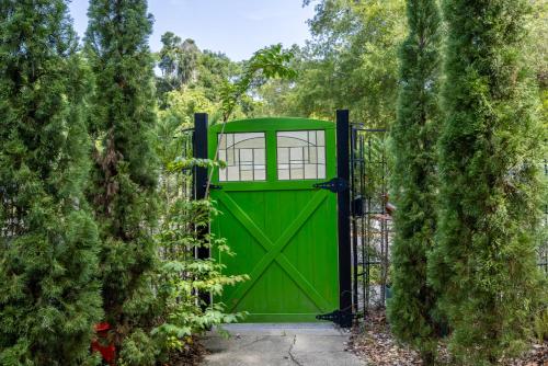 a green gate in a garden with trees at Luxury Retreat Just Steps from UF Main Campus in Gainesville