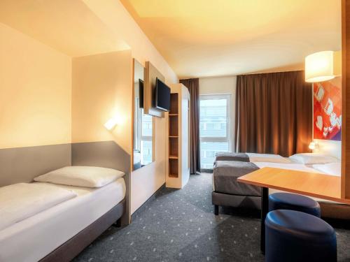 a hotel room with two beds and a table at B&B Hotel Stuttgart-Bad Cannstatt in Stuttgart