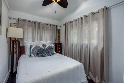 a bedroom with a white bed with a ceiling fan at Luxury Retreat Just Steps from UF Main Campus in Gainesville