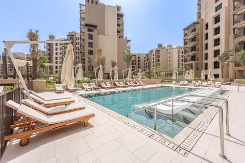 a swimming pool with lounge chairs and a hotel at Free housekeeping visits during your stay - StayShort - MJL Apartment for 4 people near Water Parks in Dubai