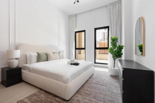 a white bedroom with a white bed and a table at Free housekeeping visits during your stay - StayShort - MJL Apartment for 4 people near Water Parks in Dubai