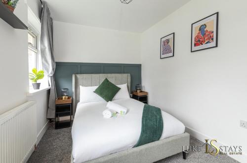 Un dormitorio con una cama blanca con detalles verdes en Luke Stays - Gray Ave, en Sherburn Hill