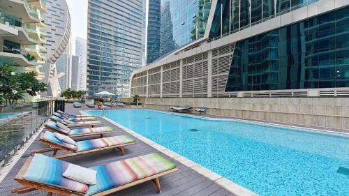 a swimming pool with chaise lounge chairs next to a building at Free housekeeping visits during your stay - StayShort - Business Bay for 4 people with City Views in Dubai